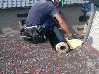 掃除後の古い屋根材の上に新しい防水紙を敷設していきます